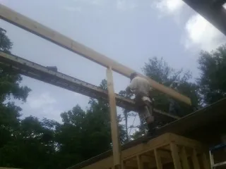Carpenter setting a ridge beam over a new addition frame — Ice Dam Removal by Roofing Brothers in Raymond