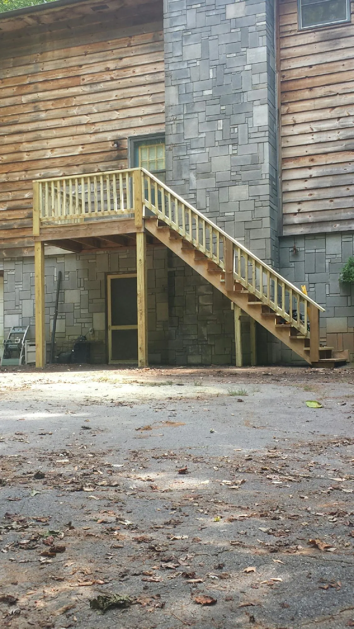 New pressure treated deck and stair landing on a log home in Raymond